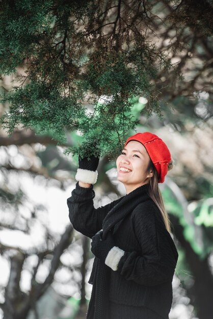 Retrato de mujer joven asiática feliz en traje de invierno en el bosque con espacio de copia Concepto de vacaciones y viajes