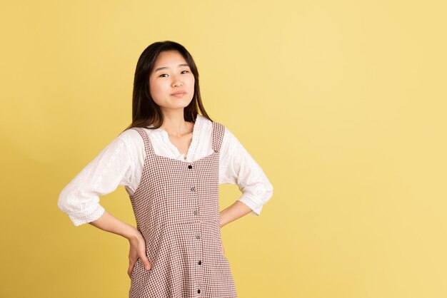 Retrato de mujer joven asiática sobre fondo de estudio amarillo Concepto de emociones humanas expresión facial anuncio de ventas para jóvenes