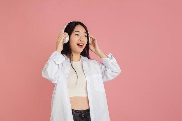 Retrato de mujer joven asiática sobre fondo de estudio rosa Concepto de emociones humanas expresión facial anuncio de ventas para jóvenes
