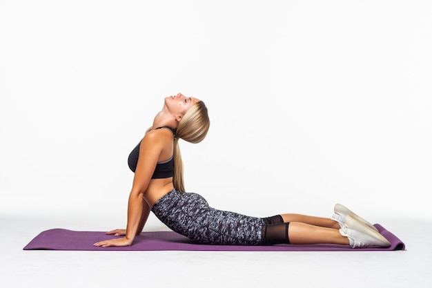 Retrato de mujer joven y atractiva haciendo ejercicios. Morena con cuerpo en forma en estera de yoga. Concepto de deporte y estilo de vida saludable. Serie de poses de ejercicio. Aislado en blanco