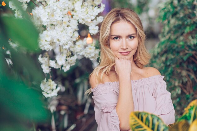 Retrato de mujer joven bastante rubia de pie en exuberante