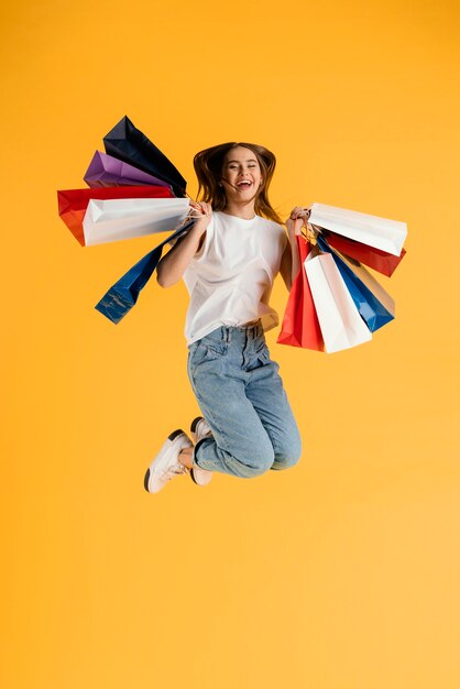 Retrato, mujer joven, con, bolsas de compras, saltar