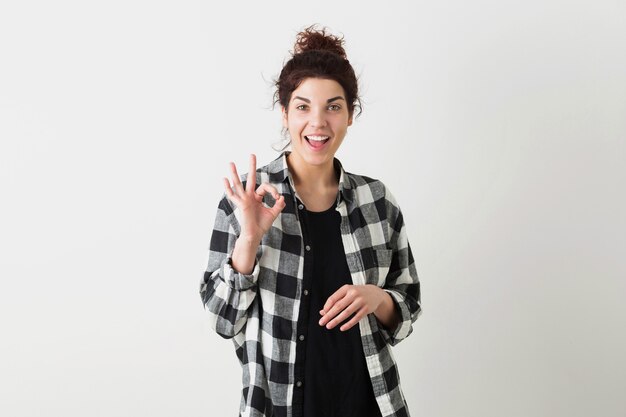 Retrato de mujer joven bonita hipster, sonriente, feliz, alegre, mostrando signo bien, gesto positivo, aislado sobre fondo blanco, camisa a cuadros