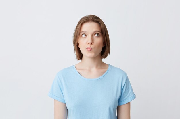 Foto gratuita retrato de mujer joven y bonita pensativa en camiseta azul pensando y se siente desconcertado