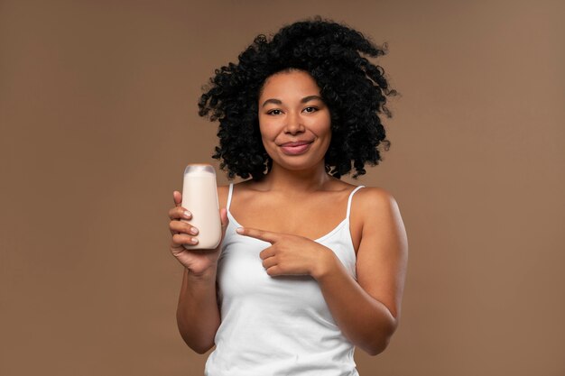 Retrato de mujer joven con botella de loción corporal