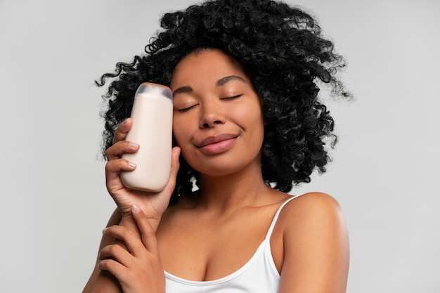 Retrato de mujer joven con botella de loción corporal