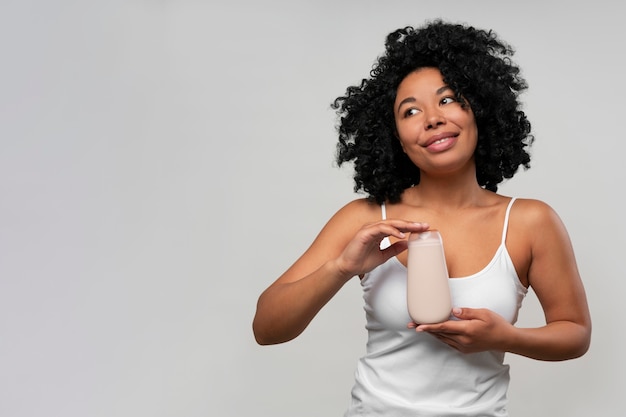 Retrato de mujer joven con botella de loción corporal