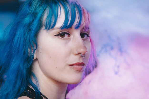 Retrato de una mujer joven con cabello rosa y azul con una expresión facial triste