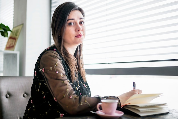 Foto gratuita retrato de una mujer joven en la cafetería