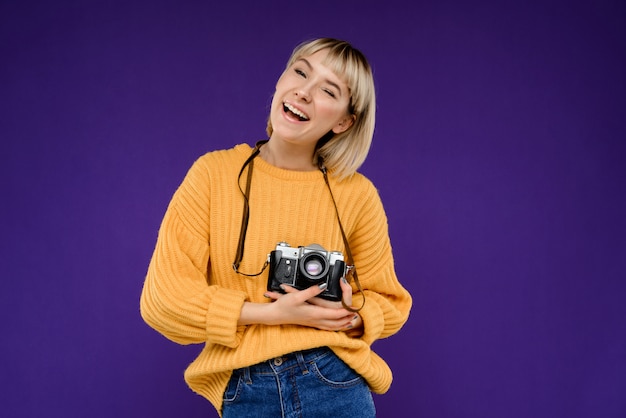 Retrato de mujer joven con cámara sobre pared púrpura