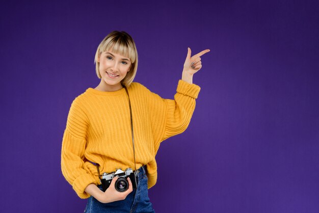 Retrato de mujer joven con cámara sobre pared púrpura