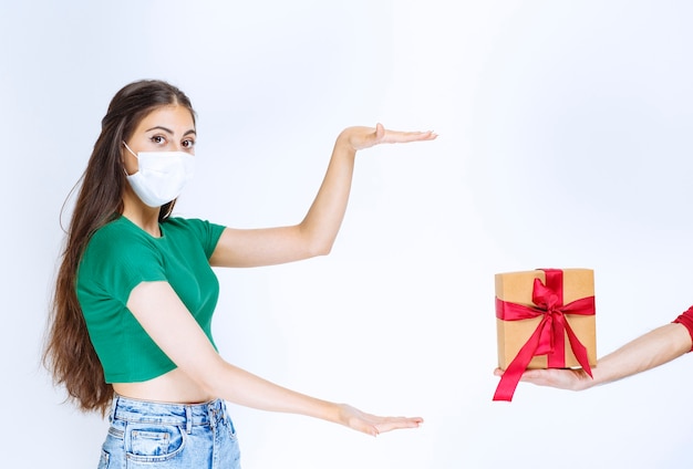 Retrato de mujer joven con camisa verde mostrando caja de regalo.