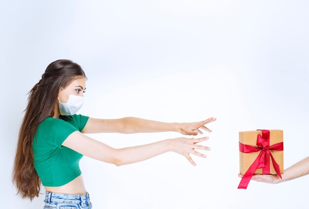 Retrato de mujer joven con camisa verde tratando de alcanzar su regalo.