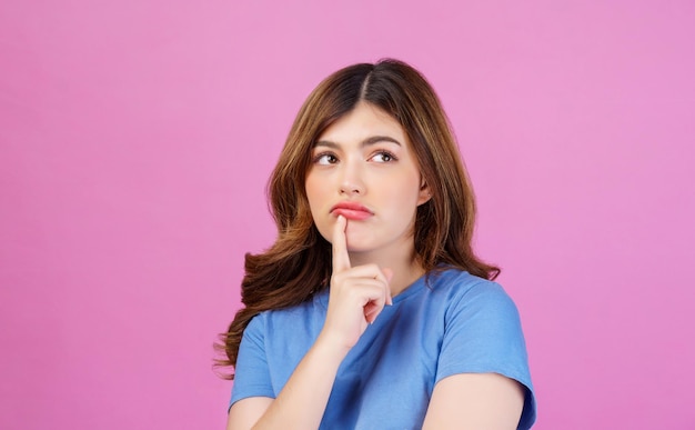 Retrato de mujer joven con camiseta casual pensando e imaginando aislado sobre fondo de color rosa