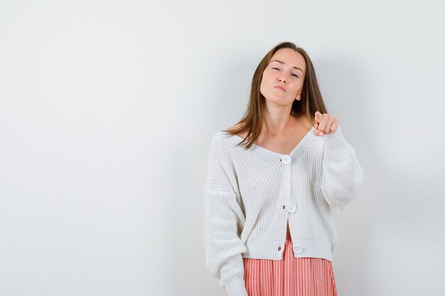 Retrato de mujer joven en cardigan mirando dudoso aislado