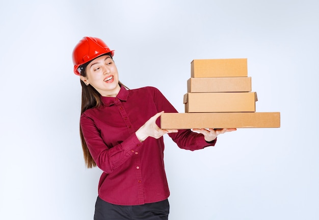 Retrato de una mujer joven en casco con cajas de papel.