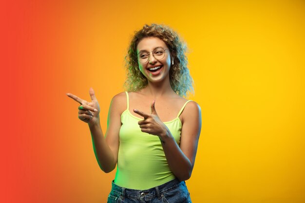 Retrato de mujer joven caucásica aislado sobre fondo de estudio degradado en neón. Modelo rizado femenino hermoso en estilo casual.