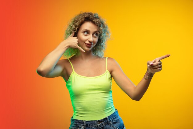 Retrato de mujer joven caucásica aislado sobre fondo de estudio degradado en neón. Modelo rizado femenino hermoso en estilo casual.