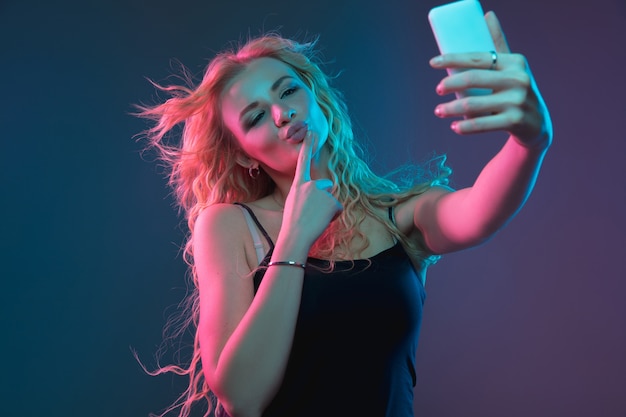 Retrato de mujer joven caucásica en el espacio degradado en luz de neón. Hermosa modelo femenina con aspecto inusual