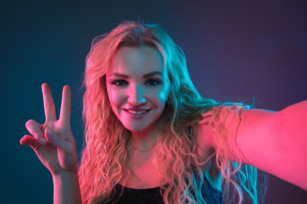 Retrato de mujer joven caucásica en el espacio degradado en luz de neón. Hermosa modelo femenina con aspecto inusual