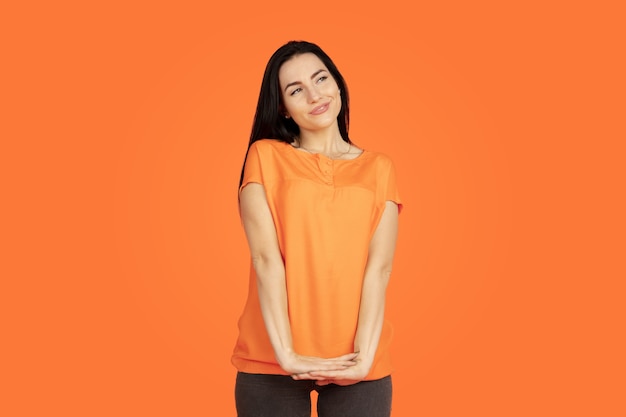 Foto gratuita retrato de mujer joven caucásica en el espacio naranja. hermosa modelo morena femenina en camisa