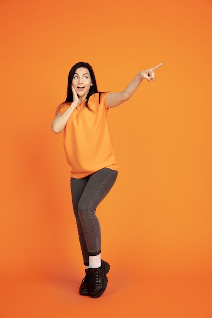 Retrato de mujer joven caucásica en el espacio naranja. Hermosa modelo morena femenina en camisa