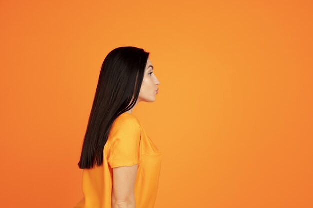 Retrato de mujer joven caucásica en estudio naranja
