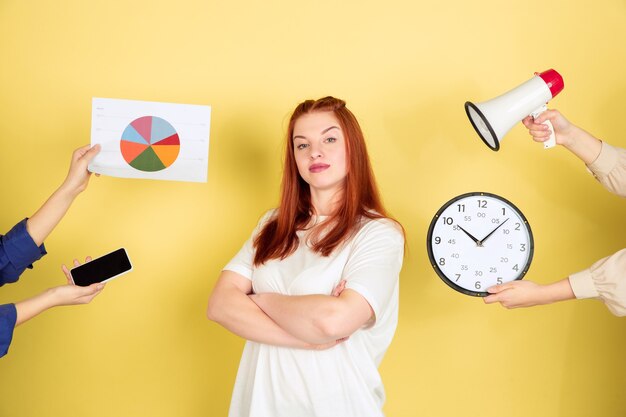 Retrato de mujer joven caucásica sobre fondo amarillo, demasiadas tareas