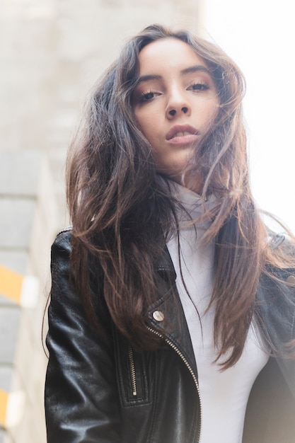 Retrato de una mujer joven en chaqueta de cuero negro mirando a cámara