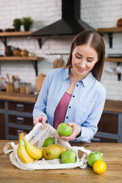 Retrato de mujer joven comprobando frutas orgánicas