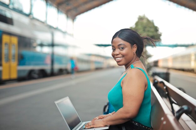 retrato, de, un, mujer joven, con, computador portatil, en, un, estación de tren