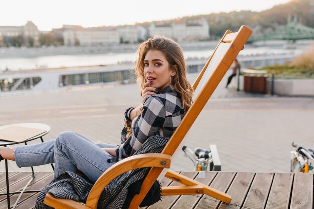 Retrato de mujer joven descansando en camisa a cuadros posando en un cómodo sillón reclinable