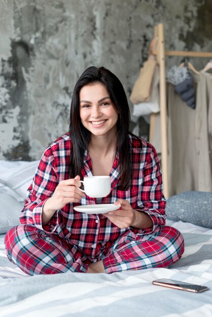 Retrato de mujer joven disfrutando de la mañana en la cama