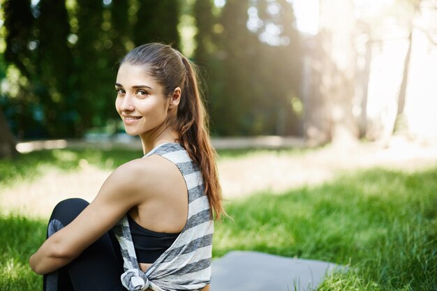 Retrato de mujer joven disfrutando de su clase de yoga en el parque en un día soleado de verano