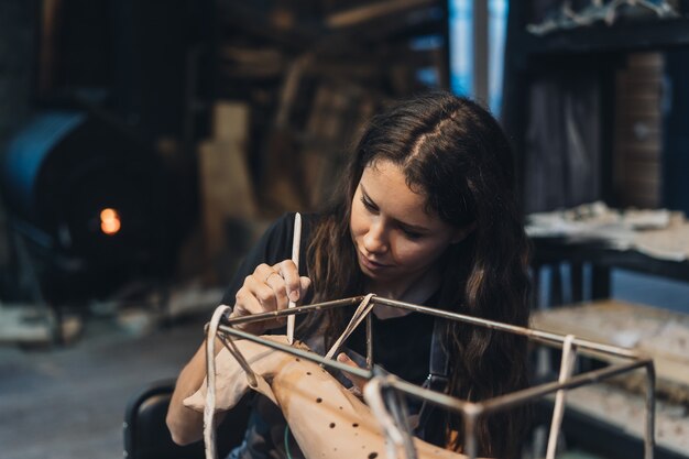 Retrato de mujer joven disfrutando de su trabajo favorito en el taller. El alfarero trabaja cuidadosamente en la ballena de arcilla