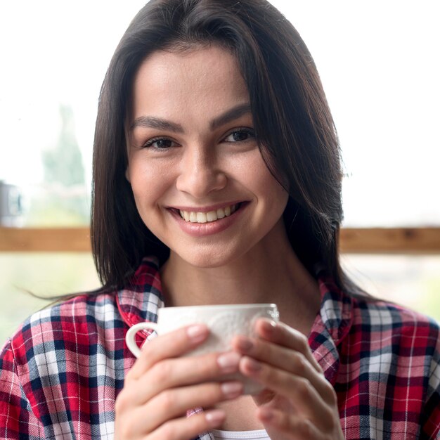 Retrato de mujer joven disfrutando de una taza de té