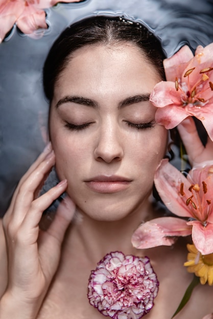 Retrato de mujer joven disfrutando de tratamiento floral