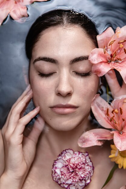 Retrato de mujer joven disfrutando de tratamiento floral