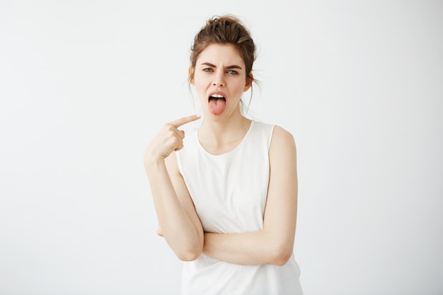 Retrato de mujer joven disgustada aburrida dedo acusador en su lengua.