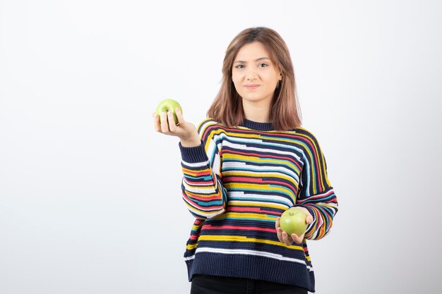 Retrato de una mujer joven con dos manzanas verdes frescas.