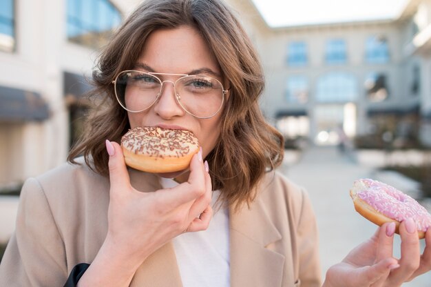 Retrato de mujer joven elegante comiendo donas