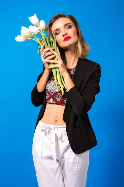 Foto gratuita retrato de mujer joven elegante con maquillaje brillante y chaqueta oscura, sosteniendo flores blancas