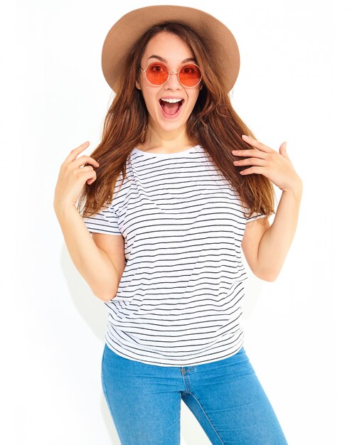 Retrato de mujer joven elegante modelo con expresión facial de sorpresa en ropa casual de verano en sombrero marrón con maquillaje natural aislado en la pared blanca. Mirando a la cámara