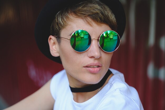 Retrato de mujer joven con elegante sombrero y gafas redondas