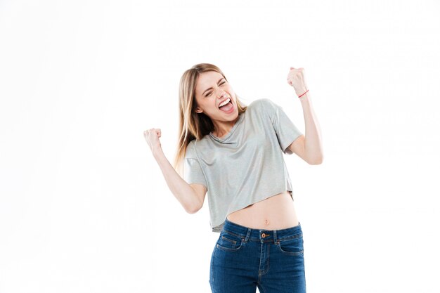 Retrato de una mujer joven emocionada feliz de pie y celebrando el éxito