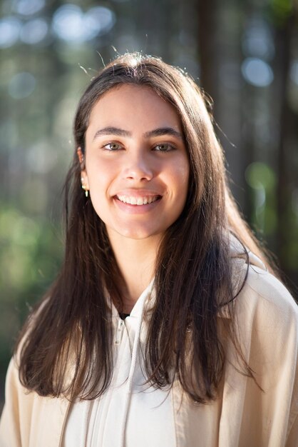 Retrato de mujer joven encantadora en el bosque. Mujer caucásica con cabello oscuro y ojos verdes sonriendo a la cámara. Retrato, naturaleza, concepto de belleza.