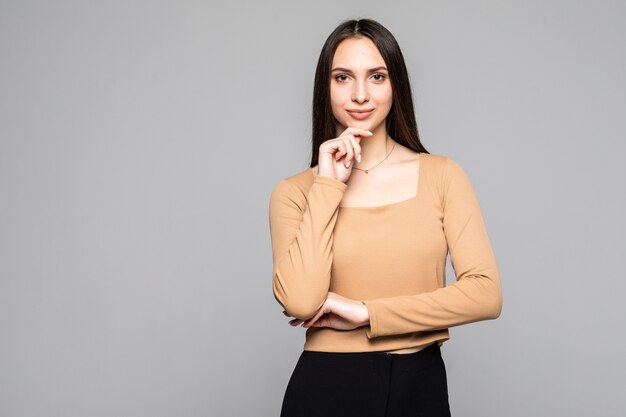 Retrato de mujer joven encantadora y encantadora mira hacia otro lado, mantenga su mano en la barbilla aislada en la pared gris con espacio para copiar texto