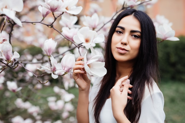 Retrato de mujer joven encantadora en flores de primavera flor árbol de magnolia