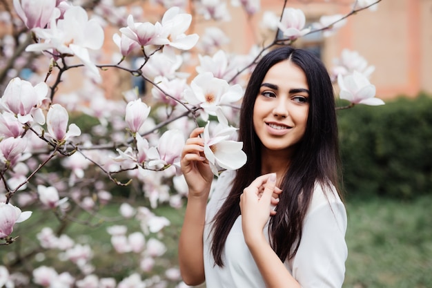 Retrato de mujer joven encantadora en flores de primavera flor árbol de magnolia