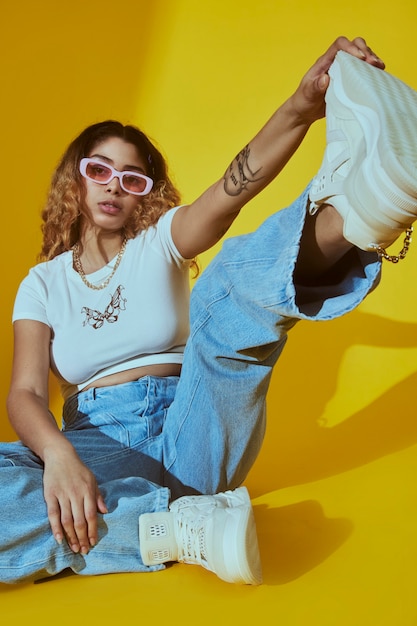 Retrato de mujer joven en estilo de moda de 2000 con jeans y gafas de sol